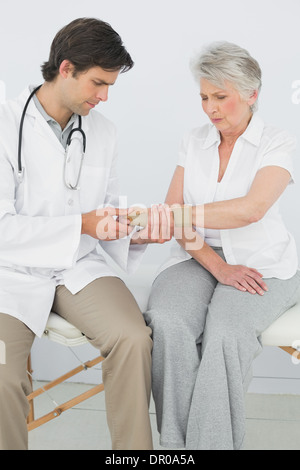 Männliche Physiotherapeut untersucht eine ältere Frau Handgelenk Stockfoto