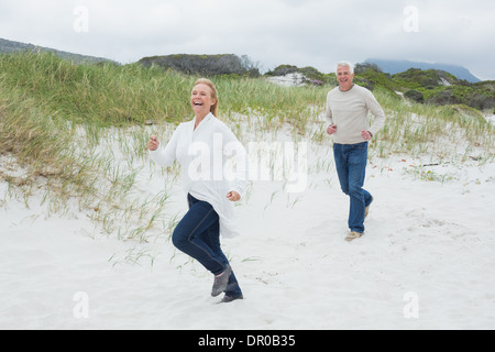 Fröhliche älteres Paar am Strand laufen Stockfoto