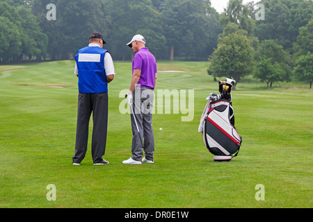 Golfer und Caddy auf dem Fairway ein Par 4 Veranstaltungsplan für Schlägerwahl zu lesen. Stockfoto
