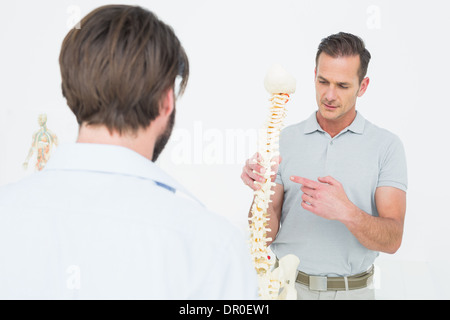 Männlichen Arzt erklären, die Wirbelsäule zu einem Patienten Stockfoto