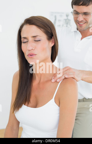 Männliche Chiropraktiker eine junge Frau Schulter Massage Stockfoto