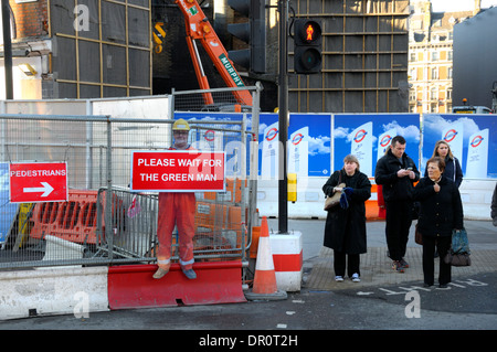 London, England, Vereinigtes Königreich. Menschen warten auf die Straße zu überqueren, von Baustellen. "Bitte warten auf grünen Mann" Zeichen Stockfoto