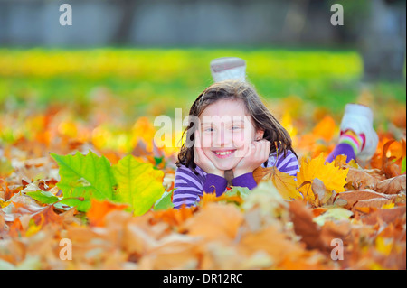 kleines Mädchen Handauflegen Herbstlaub Stockfoto