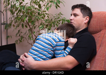 Vater umarmt seine Kind junge, sitzt zu Hause auf sofa Stockfoto