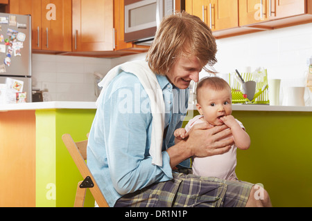 Vater Holding Baby in Küche Stockfoto