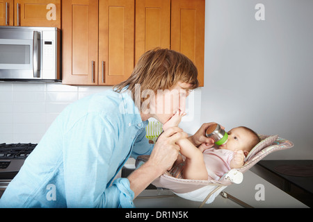 Vater küssen Baby Füße im Stuhl Stockfoto