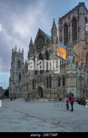 Abend in einer ruhigen, malerischen Piazza - Menschen durch Eingang Süd & Turm der prächtigen Münster gegen Dark Sky - York, North Yorkshire, England, UK. Stockfoto