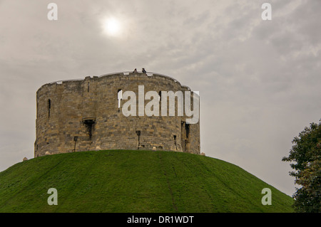 Unter grauem Himmel stehen Besucher auf hohen Wällen des Clifford's Tower - historische Burgruinen auf einem Hügel und Wahrzeichen in York, North Yorkshire, England, Großbritannien. Stockfoto