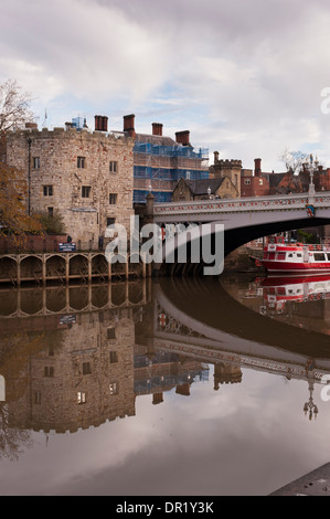 Lendal Bridge, steinerner Turm am Ufer des Flusses Ouse, festgeklemmtes Stadtkreuzfahrtschiff, das sich im Wasser spiegelt, Menschen zu Fuß - landschaftlich reizvolle York, North Yorkshire, England, Großbritannien. Stockfoto