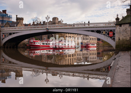 Menschen, die die Lendal Bridge überqueren und festfahrende Kreuzfahrtboote spiegeln sich im ruhigen Wasser des Flusses Ouse wider - malerisches Stadtzentrum von York, North Yorkshire, England. Stockfoto