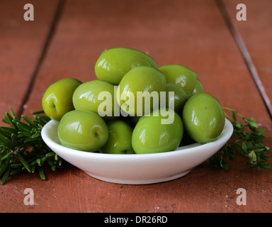 Marinierte Oliven in Schüssel auf einem Holztisch Stockfoto