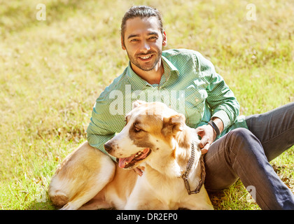 Mann und zentraler Asiatischer Schäferhund spazieren im Park. Er hält den Hund an der Leine. Stockfoto