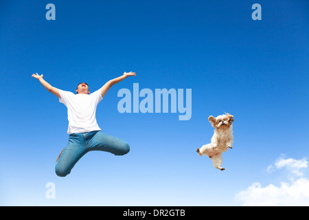 glücklicher junger Mann und Hund zusammen in den Himmel springen Stockfoto