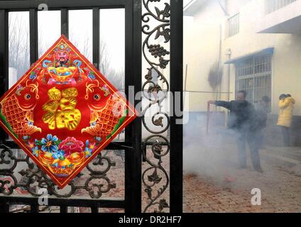 Zhengzhou. 18. Januar 2014. Foto aufgenommen am 3. Februar 2011 zeigt einen Dorfbewohner Verrechnung Feuerwerk zu begrüßen das neue Jahr in Xinzheng Stadt, Zentral-China Henan Provinz. Das chinesische Schriftzeichen "Fu", was "Glück" bedeutet, ist überall in China während des Frühlingsfestes üblich. Es ist beliebt für seine günstigen Bedeutung, auch als "Glück", das die Chinesen glauben wird Ihnen Segen im kommenden neuen Jahr interpretiert werden können. © Wang Song/Xinhua/Alamy Live-Nachrichten Stockfoto
