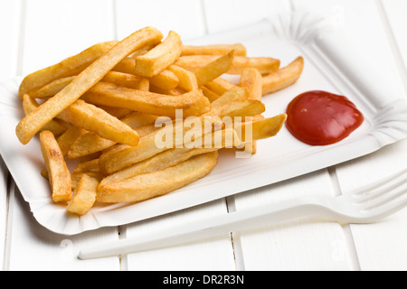Pommes Frites mit Ketchup auf Pappteller auf weißer Holztisch Stockfoto