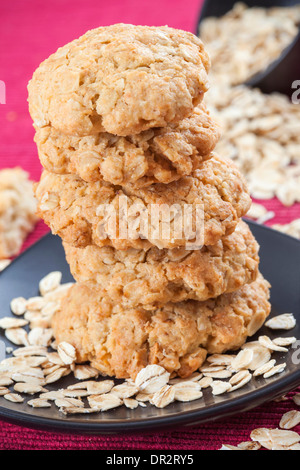 Fünf Haferkekse auf rotem Grund, verstreuten Haferflocken Stockfoto