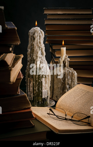 eine schmelzende Kerze in einer Flasche unter alten Büchern Stockfoto