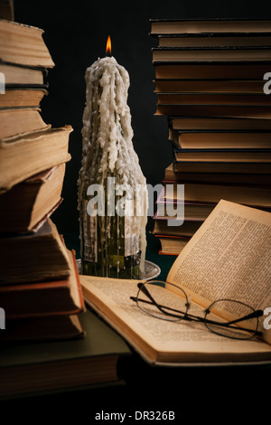 eine schmelzende Kerze in einer Flasche unter alten Büchern Stockfoto