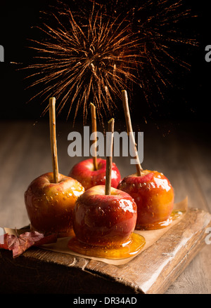 Gruppe von Toffee Äpfel auf rustikalem Holzbrett mit Feuerwerk im Hintergrund Stockfoto