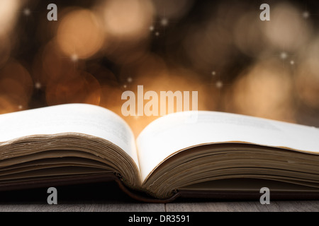 Offenes Buch auf Holztisch mit Bokeh-Effekt im Hintergrund Stockfoto