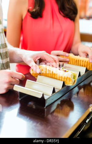 Hotdog - junge Kunden in einer Snackbar essen leckere Fastfood Würstchen Stockfoto