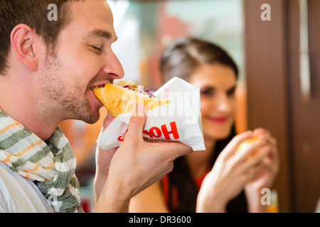 Hotdog - junge Kunden in einer Snackbar essen leckere Fastfood Würstchen Stockfoto