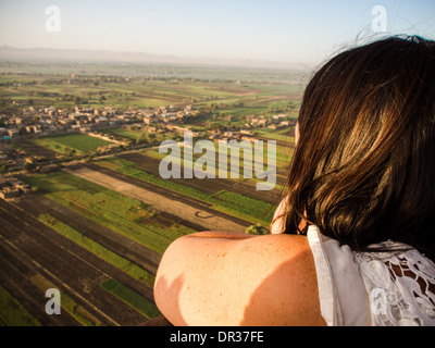 Eine Frau wacht die ägyptische Landschaft vorbeischweben aus einem Heißluftballon über dem Westufer des Nils in Luxor, Ägypten. Stockfoto