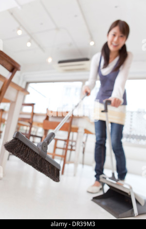Junge Frau fegt Stock im café Stockfoto