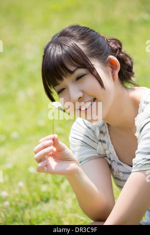 Junge Frau sitzt auf Rasen Stockfoto