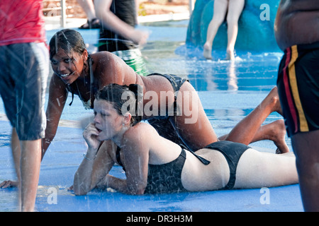 Junge weiße Mädchen im Bikini & Aborigines junge liegen nebeneinander im seichten Wasser Colling aus im Sommer in Hervey Bay Wasserpark Stockfoto