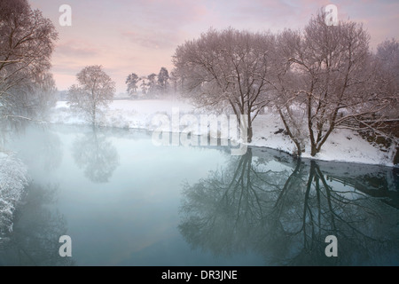 Schnee bedeckt die Felder und Bäume säumen den Fluss Avon bei Bilovec, Worcestershire, durch die alte Brücke. Stockfoto