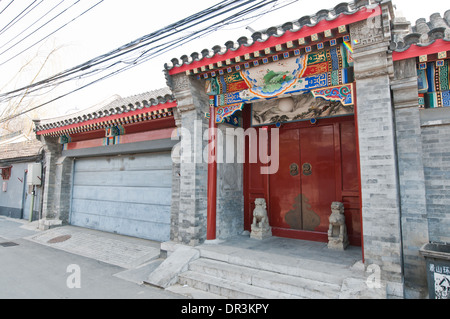 rote Tür mit zwei steinernen Löwen Menduns Gebiet Hutong in Peking, China Stockfoto