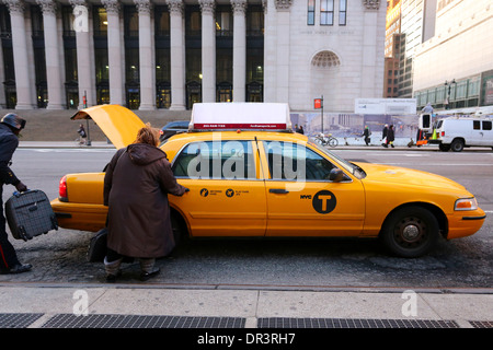 Eine Person, die vor der Penn Station in New York City in ein Taxi steigt, der Fahrer, der Gepäck in den Truck des Fahrerhauses bringt Stockfoto