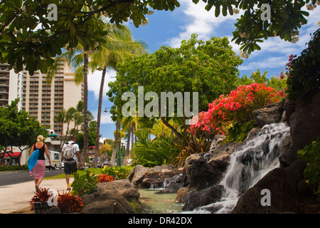 Blumen und Wasserfall Brunnen am Kuhio Beach Park, Waikiki Beach, Honolulu, Oahu, Hawaii Stockfoto