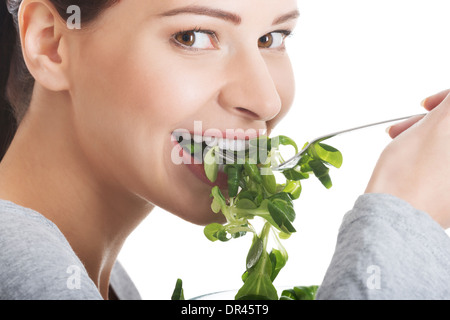 Casual Mädchen essen Feldsalat. Isoliert auf weiss. Stockfoto