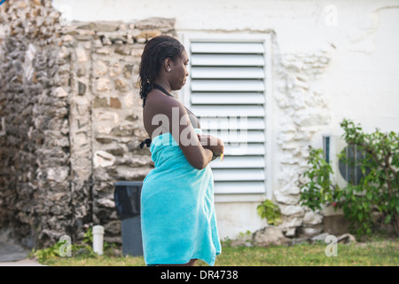 Nach dem Schwimmen in der Karibik steht eine junge afroamerikanische Frau im Badeanzug in ein Handtuch gewickelt. Stockfoto