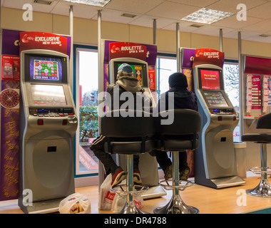 Der Mann und die Frau zu festen Quoten Spielautomaten (FOBT terminal Wetten zu festen Quoten) in Ladbrokes Betting Shop. Großbritannien Stockfoto