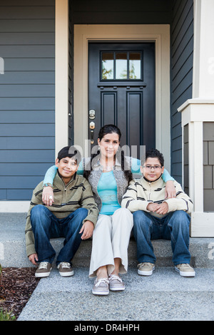 Hispanische Mutter und Söhne sitzen am vorderen stoop Stockfoto