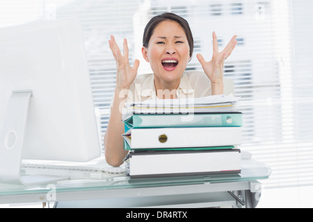 Wütend Geschäftsfrau mit Stapel der Ordner am Schreibtisch schreien Stockfoto