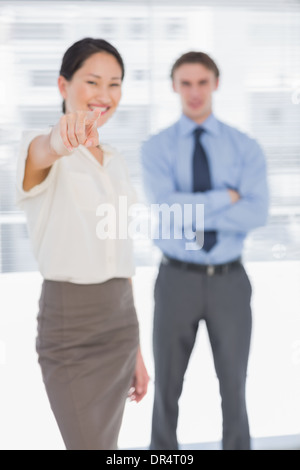 Geschäftsfrau zeigt in Richtung der Kameras mit Mann im Büro Stockfoto