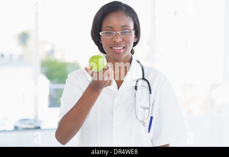 Porträt einer lächelnden Ärztin hält einen Apfel Stockfoto