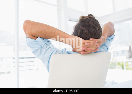 Rückansicht des ein legerer Mann mit Händen hinter dem Kopf im Amt ruhen Stockfoto