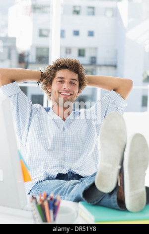 Entspannte legerer Mann mit den Beinen am Schreibtisch im Büro Stockfoto