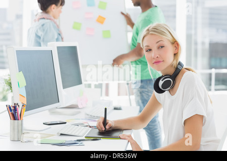 Künstler Zeichnung etwas auf Grafiktablett mit Kollegen hinter im Büro Stockfoto