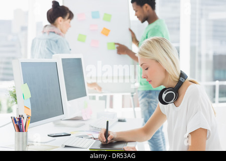 Künstler Zeichnung etwas auf Grafiktablett mit Kollegen hinter im Büro Stockfoto