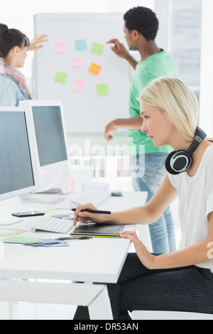Künstler Zeichnung etwas auf Grafiktablett mit Kollegen hinter im Büro Stockfoto