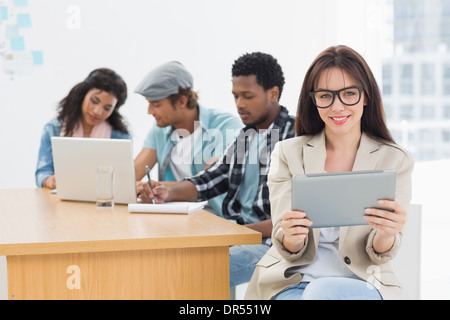 Frau mit digital-Tablette mit Kolleginnen und Kollegen hinter im Büro Stockfoto