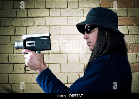 Mann mit langen Haaren, die Dreharbeiten mit Vintage Filmkamera Stockfoto