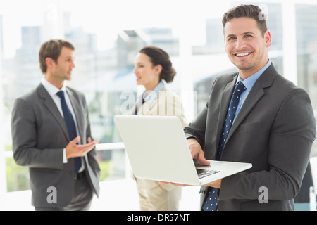 Geschäftsmann mit Laptop mit Kollegen diskutieren im Büro Stockfoto