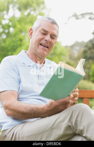 Senior Mann liest ein Buch im park Stockfoto